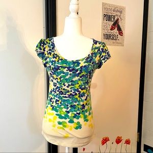 Cream shirt with blues and greens that resemble leaves on a cap sleeve shirt